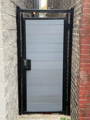 Custom fabricated pedestrian gate between houses , made with European green wood and locking keypad .