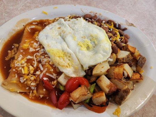 Breakfast cheese/onion enchiladas with over easy eggs and mild red sauce. Home fries and whole beans.