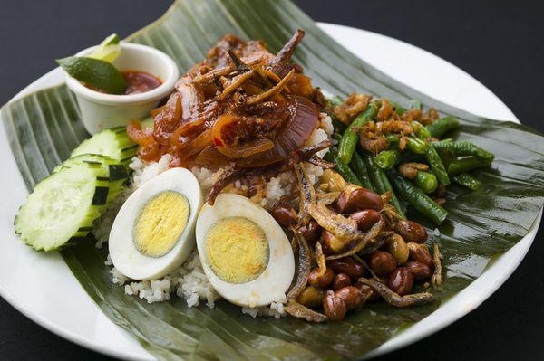 Nasi Lemak, the national dish of Malaysia. Coconut rice topped with sambal anchovy, beef rendang, peanut, string bean, cucumber, egg.