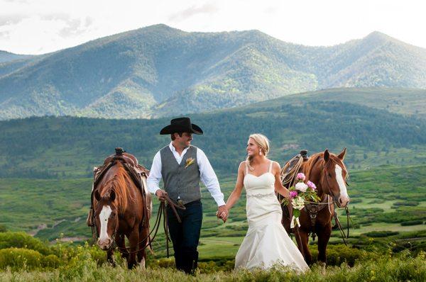 A bride and groom walking their horses on their ranch after their ceremony.