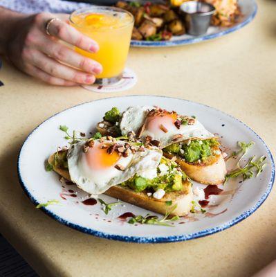 Avocado Toast at Brunch: Toasted sourdough bread, fresh smashed avocado, feta cheese, toasted pecans, balsamic reduction, sunny-side-up eggs