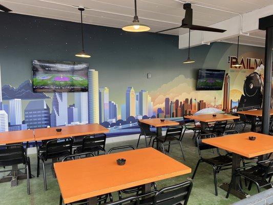 Covered patio with TV's and mural of the Houston skyline