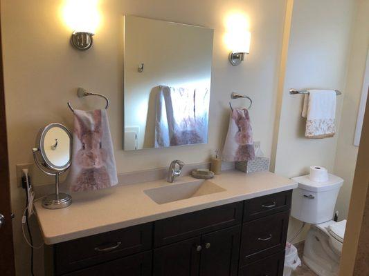 A single vanity that shows a custom trough sink formed from the same material as the countertops for a continuous and seamless look.