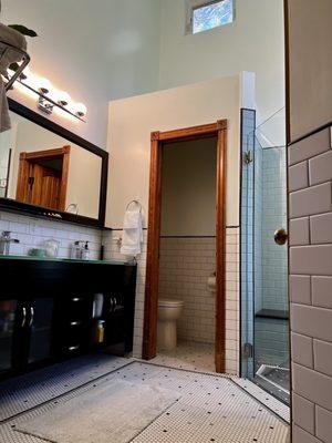 Master bathroom with penny tiled bordered floor, walk in shower, subway tile wainscoting and freshly painted high ceiling