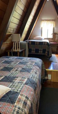 The upstairs bedroom with two twin beds and windows at each end.