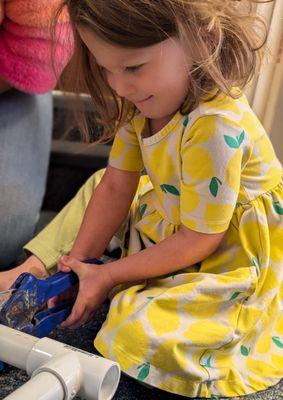 A preschool student uses a tool to cut a PVC pipe when the class constructed a scarecrow for the Idaho Botanical Garden Scarecrow Stroll.