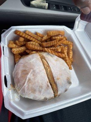 Philly cheesesteak on a bun with a side of crispy fries