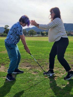 Coach Jenn positioning her student for a successful swing!