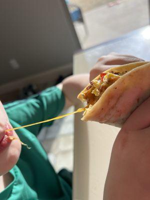 My kiddo enjoying the cheesy goodness of his bacon egg breakfast taco!