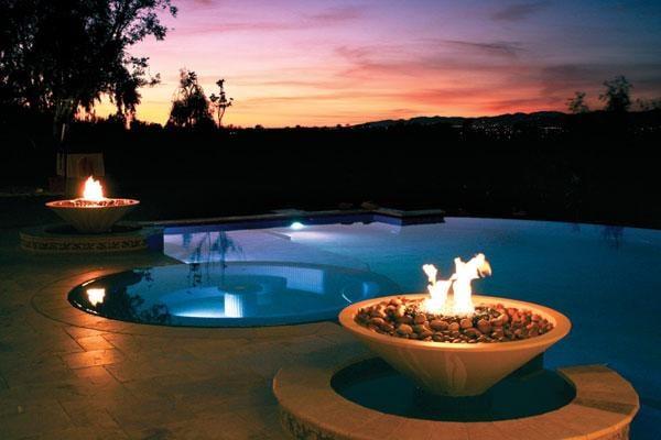 Vanishing edge pool over looking the valley with a beautiful sunset. Fire bowls illuminate around the spa.