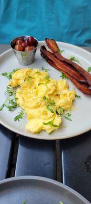 Creamy scrambled eggs with side of bacon.