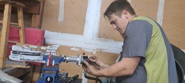 Zack, the head mechanic changing the pulley of a supercharger in a vice while protecting the shaft.