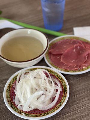 Pickled onions, rare steak on the side with a small bowl of hot broth