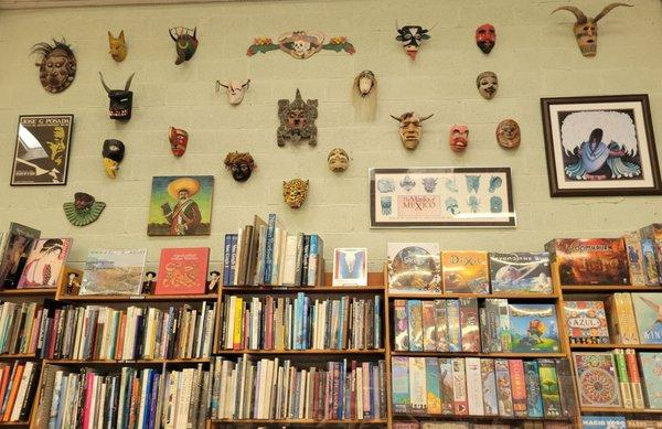 Mask collection high on the wall above the book shelves