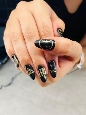 Natural nail manicure with nail art. Black matte polish  with gold Harry Potter hand drawn design #Halloweennails