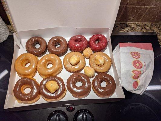 An assorted dozen along with a few glazed doughnut holes along with two apple fritters in the bag.