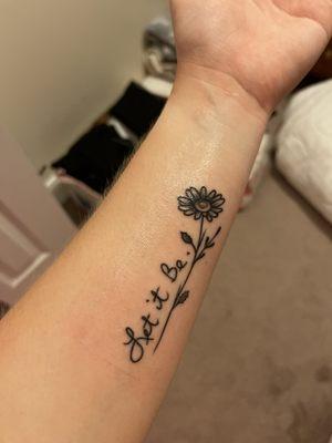 Simple flower and letter tattoo on left forearm