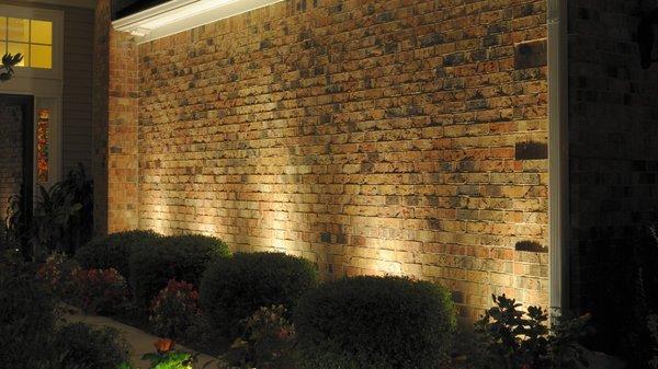 Illuminated wall beside the walkway to entrance provides reflected light for safety and security.