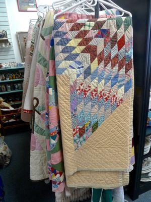 Rack full of vintage quilts and spreads.