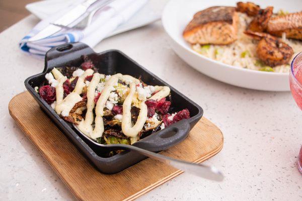 Crispy Brussels Sprouts topped with goat cheese, dried cranberries and pesto aioli (contains nuts).