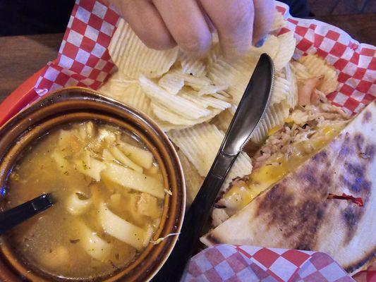 Rio Grande sandwich with chicken noodle soup and chips. The sandwich has pastrami, turkey, ham, green chile