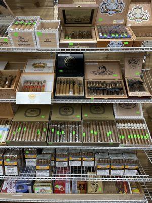 Wide collection of cigars in a variety of sizes and shapes available in store and are stored in humidor shelves. Come and get one.