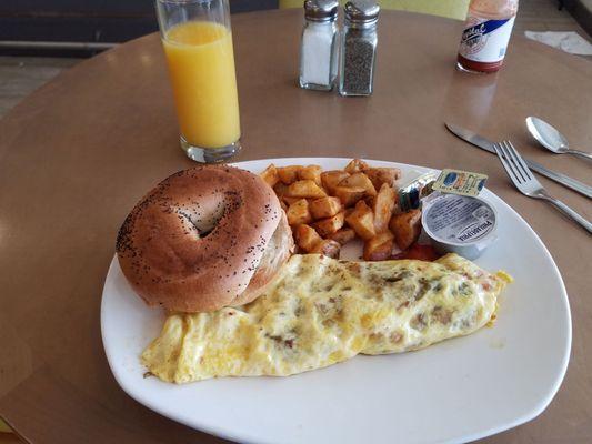 Omelet with ham, taters and a bagel.