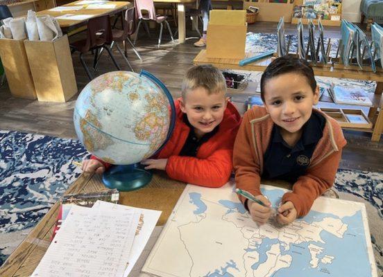 Elementary school children working on world map and geography skills in a Montessori classroom