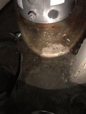 More water and debris extending out from the water heater.