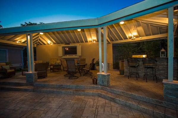 Raised and covered patio with an outdoor kitchen, grill, bar area, dining patio furniture, and sitting area with an outdoor TV!