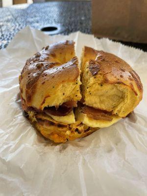 Breakfast bagel sandwich: egg, bacon, tomato on a cheddar bagel.