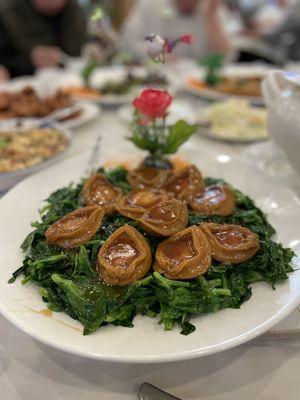 Braised whole abalone on a bed of sautéed pea shoots.