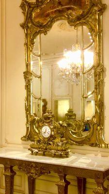 Gold gilded mirror, rococo clock on a Marble top table