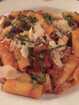 Rigatoni pasta with tomato sauce and sausage, portobello mushrooms, Parmesan cheese, topped with fresh basil