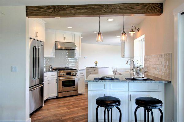 Clean kitchen design with stainless steel appliances, shaker cabinets, farmhouse sink and textured subway tile.