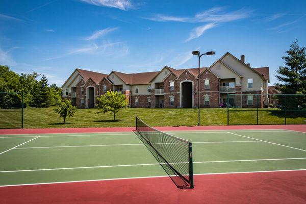 Tennis courts with some of our open green spaces in background. Back of apartment building showing patios & balconies.