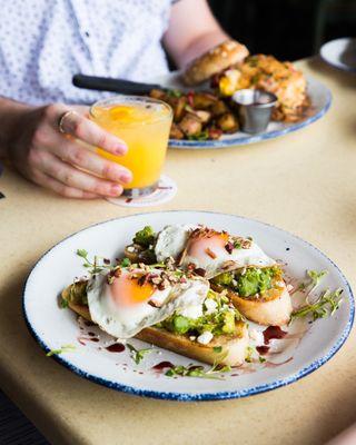 Avocado Toast at brunch: Toasted sourdough bread, fresh smashed avocado, feta cheese, toasted pecans, balsamic reduction, sunny side up eggs