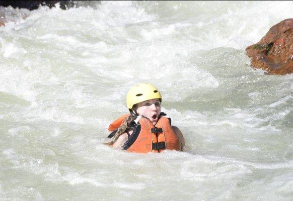 One of three occupants basically being waterborne by the river while Hannah is having the time of her life on the raft.