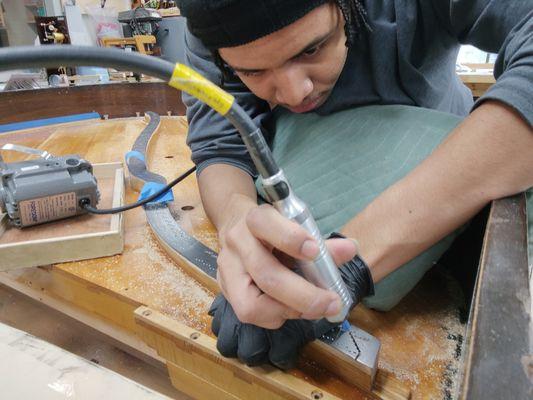 Wesley drilling holes in the bridge of a piano.