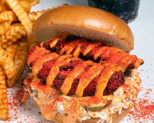 Two Nashville style hand breaded chicken tenders in between a toasted brioche hamburger bun with coleslaw, pickles, aioli and Hot Cheeto