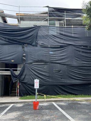 Scaffolding and netting around building and over entrance.