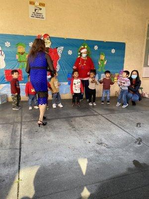 The toddlers singing jingle bells and the teachers helping them stay focused on singing.