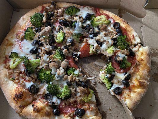 Personal pizza with pepperoni, sausage, broccoli, and olives.