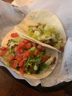 Special taco of the day jerk pork taco with jerk sauce and salsa verde alongside fried chicken taco.