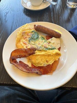 Custom omelet with spinach, tomatoes, ham, and cheddar cheese. Some bacon and sausage on the side.