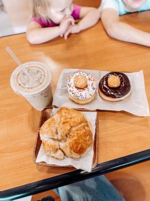 Yummy donuts, sausage and egg croissant and iced coffee.