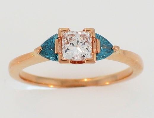 14 karat Rose Gold ring with 0.53 carat princess-cut diamond and 0.20 carat total weight blue diamond trillion-cut side stones.