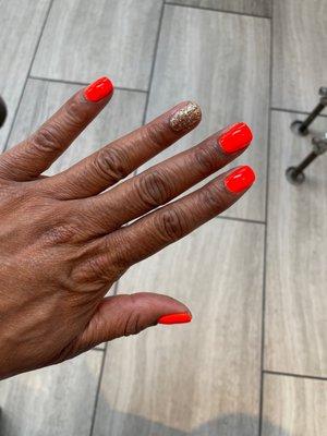 Manicured hands with orange and glitter Polish.