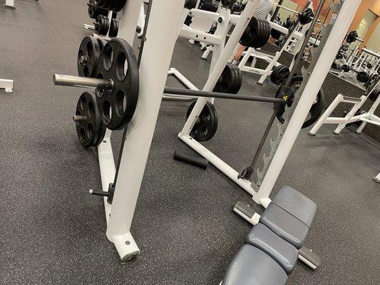 Person left their weights and bench at smith machine. The other machine also has a bench. And, the third is in use.