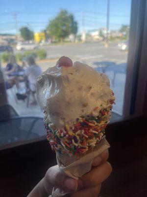 Two scoops of Piña colada in a chocolate covered sprinkled cone.